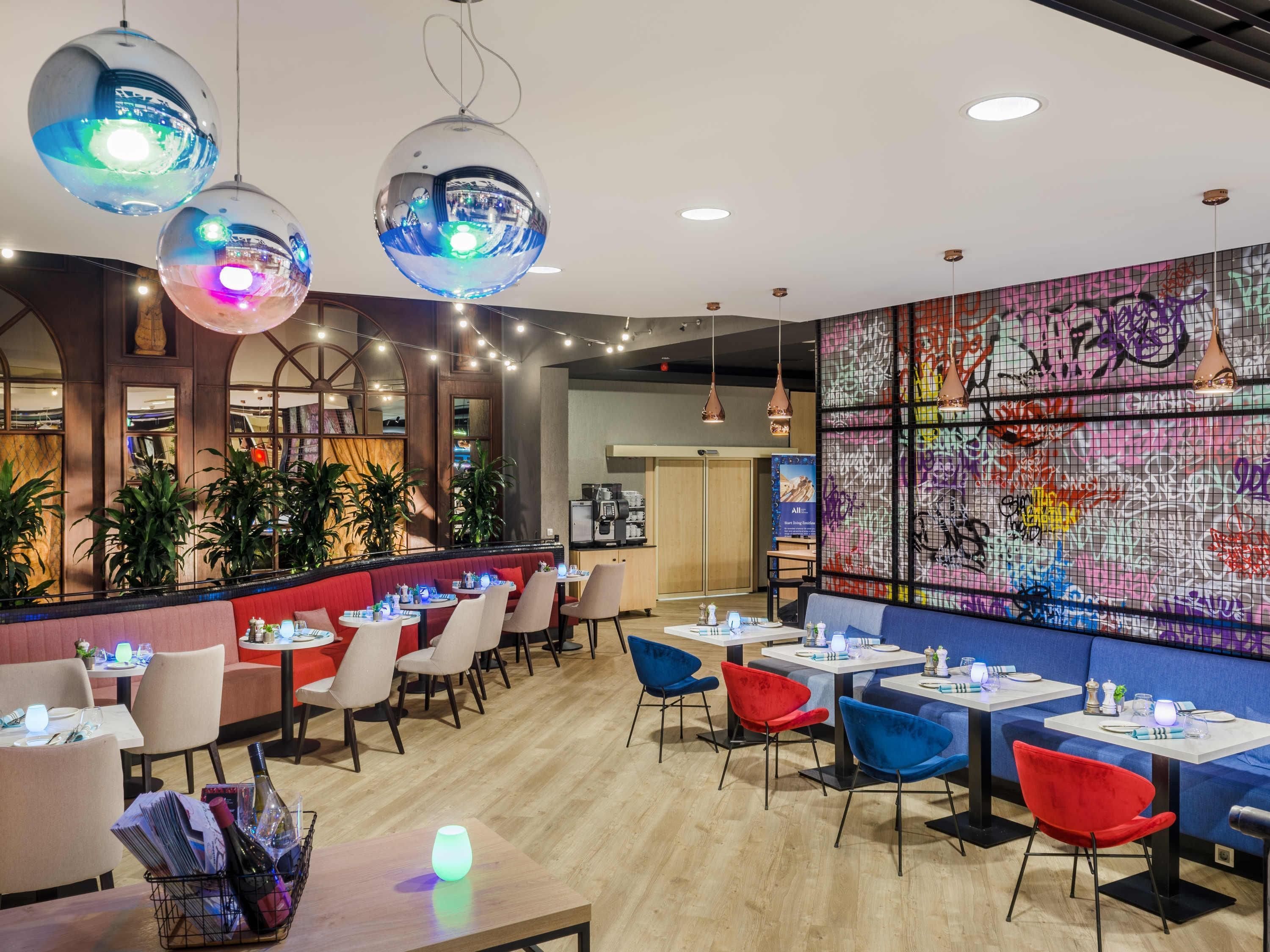 Un restaurante con mesas redondas, sillas y una pared con grafitis.