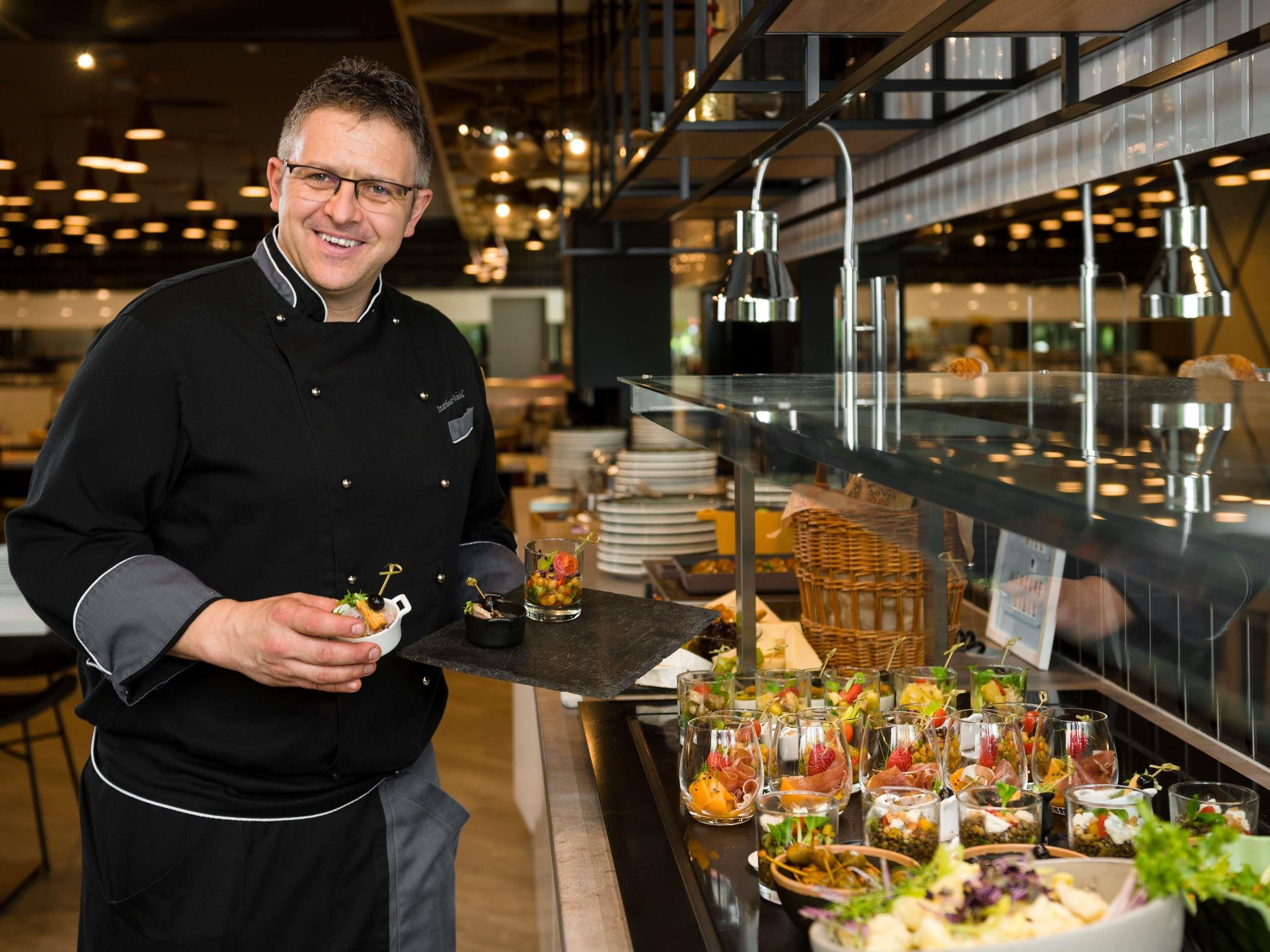 A chef holding a tray with appetizers in a modern restaurant setting.