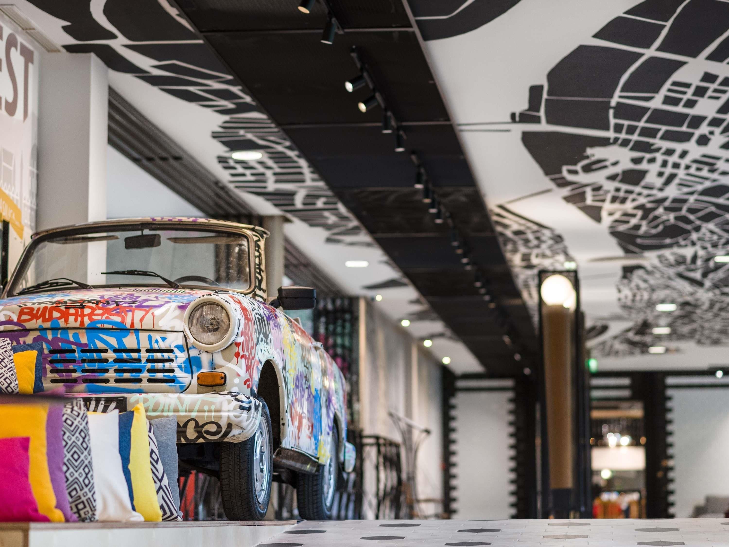 Ein Fahrzeug mit Graffiti, eine Decke mit geometrischem Muster und ein Fliesenboden.