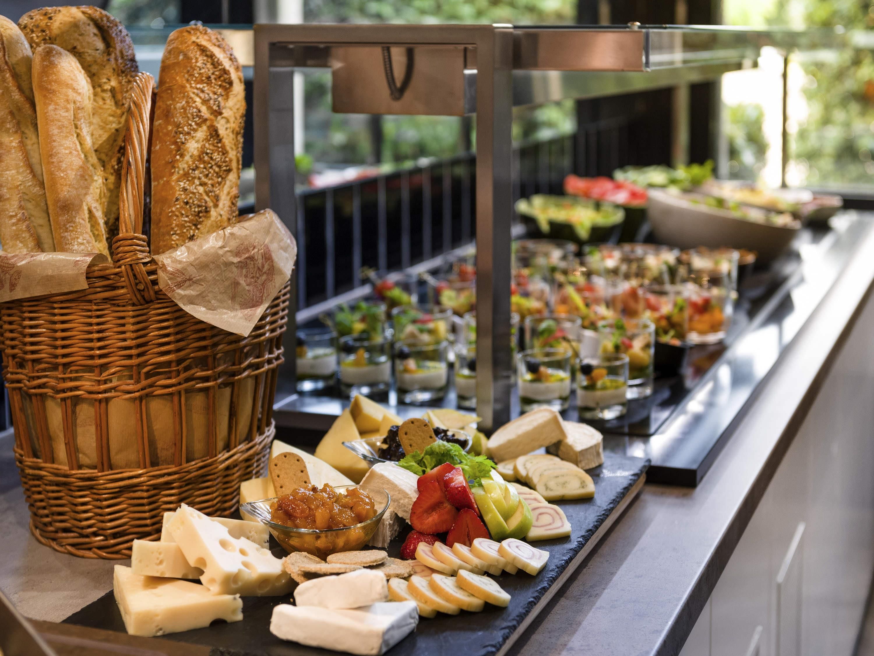 A buffet with various cheeses, fruits, and bread.