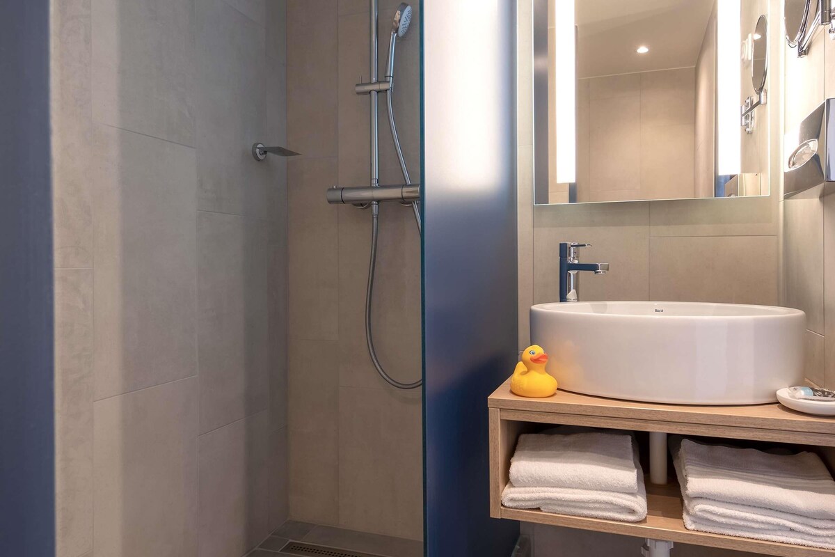 Un baño moderno con ducha, lavabo y espejo.