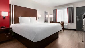 Una habitación de hotel con una cama grande, mesitas de noche, un escritorio y una silla.