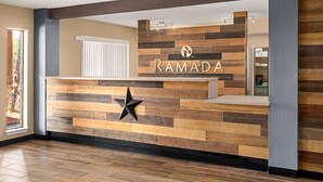 Una recepción con diseño de paneles de madera y el nombre "RAMADA" exhibido en la parte superior.