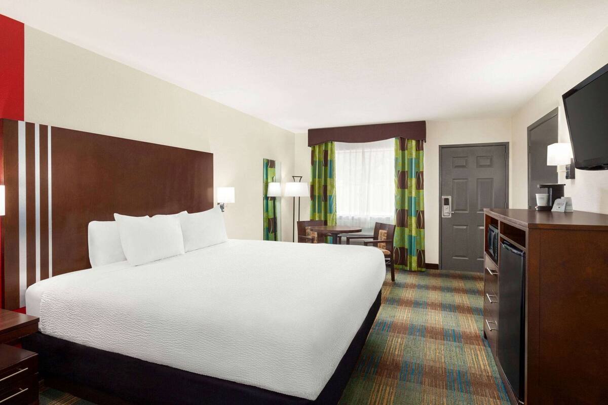 Une chambre d’hôtel avec un grand lit, un bureau, une chaise, une télévision et une porte.