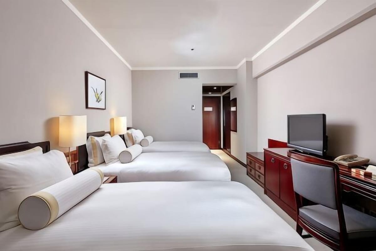 Quarto de hotel com duas camas, televisão, mesa e uma cadeira.