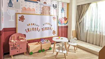 Een kinderspeelkamer met een whiteboard, houten speelgoed en een kleine tafel.