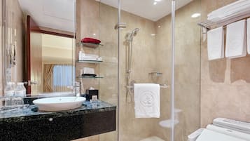Un baño moderno con ducha envuelta en vidrio, lavamanos de mármol y un inodoro con panel de control.