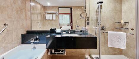 Un baño moderno con bañera, ducha, tocador con lavamanos y cabina de ducha con mampara de vidrio.