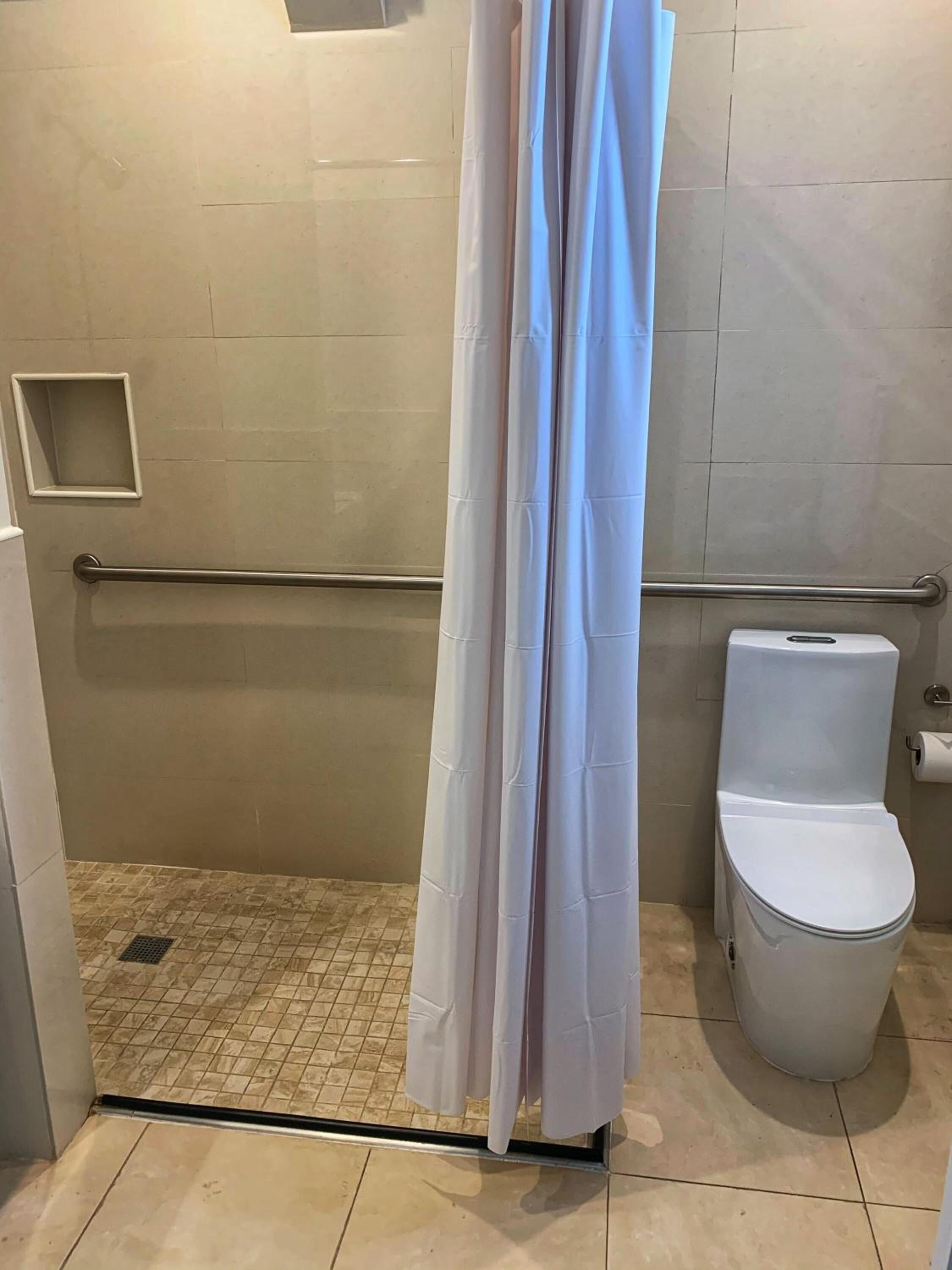 Kylpyhuone, jossa on suihku, wc ja pieni hylly.