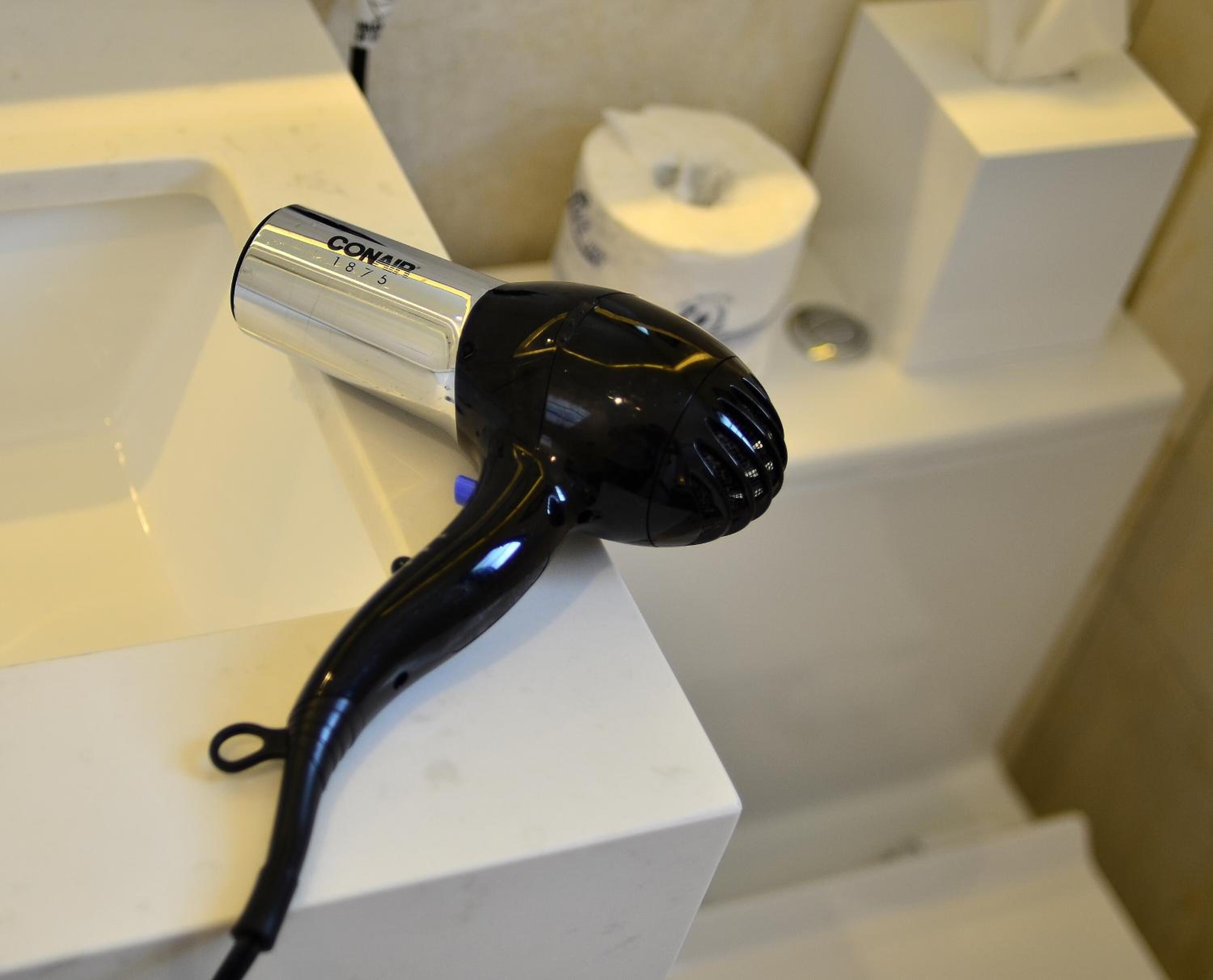 A black hairdryer with a silver base on a white countertop.