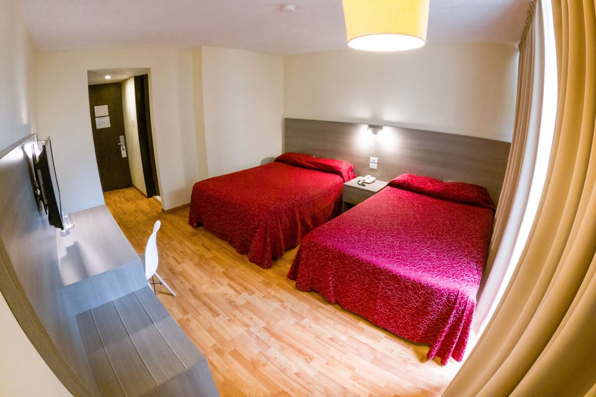 Habitación de hotel con dos camas, un escritorio, un teléfono y una puerta.