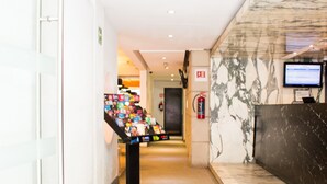 A hotel lobby with a reception desk, a display of magazines, and a marble wall. - Hotel del Angel Reforma (Mexico City)