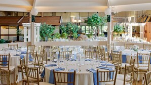 A spacious indoor dining area with multiple tables and chairs, large windows with a view of greenery, and a modern architectural design.