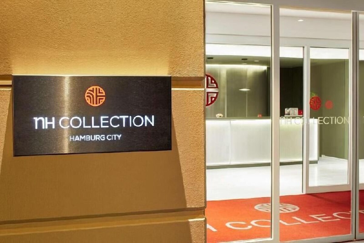 A hotel entrance with a sign reading 'NH COLLECTION Hamburg City' and a glass door leading inside.