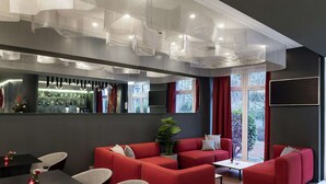 A modern interior with red sofas, a bar area, and large windows. - NH Collection Hamburg City (Hamburg)