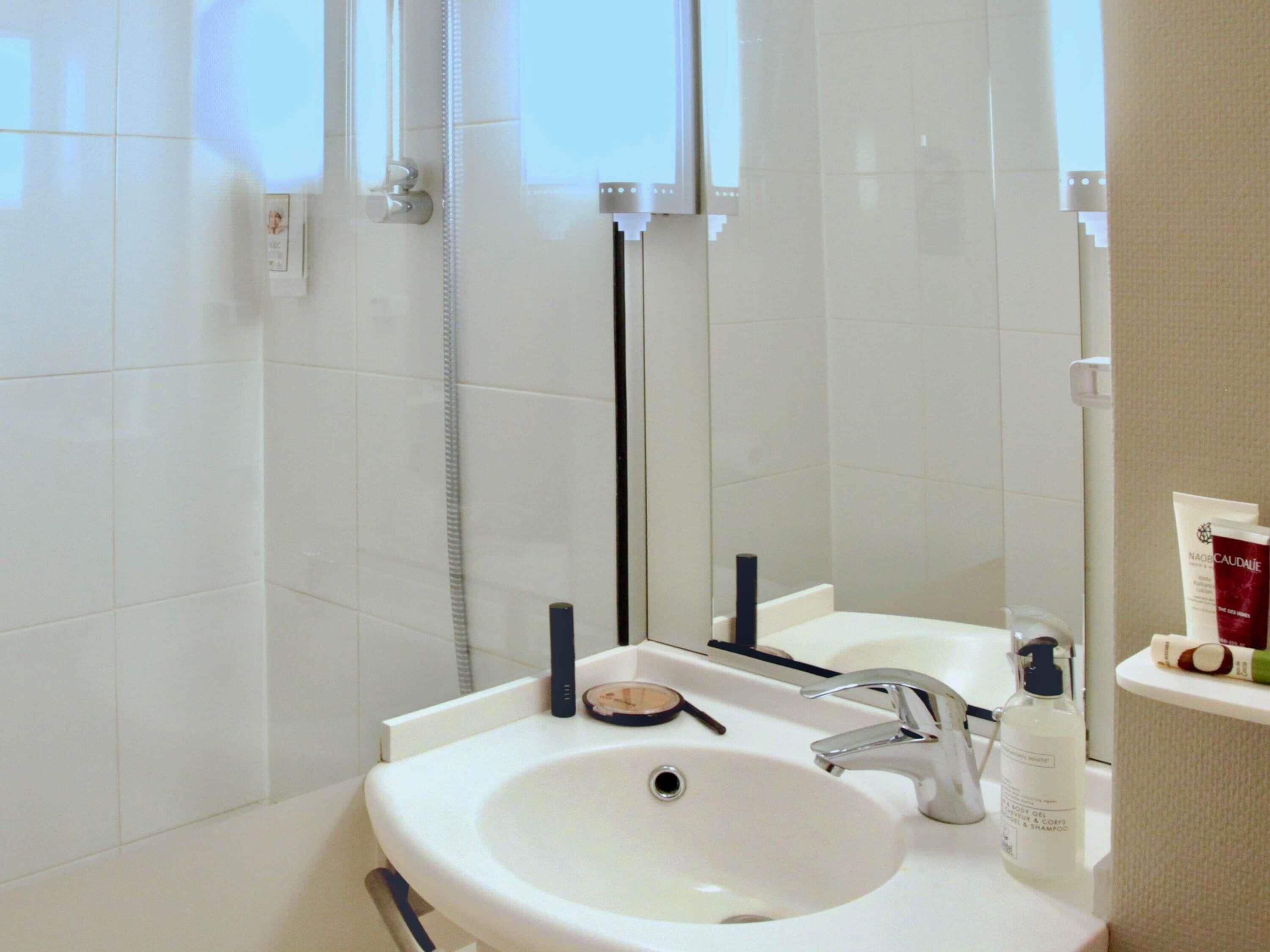 A bathroom with a white sink, a mirror, and a shower area.