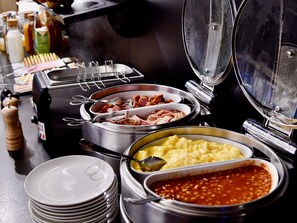 A buffet with various food options including meats, potatoes, and beans.