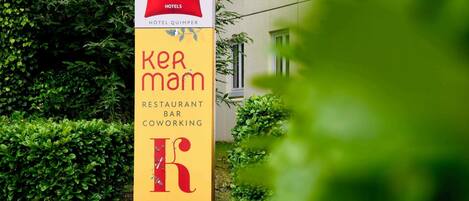 Letrero que indica 'ibis Hotels' y 'ker mam', con restaurante, bar y espacio de coworking.