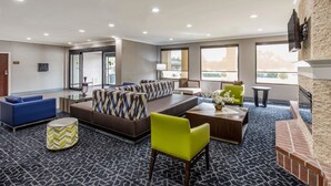 A modern lobby with a sectional sofa, a bright green chair, a coffee table, and a fireplace. - Comfort Inn College Park North (Beltsville)
