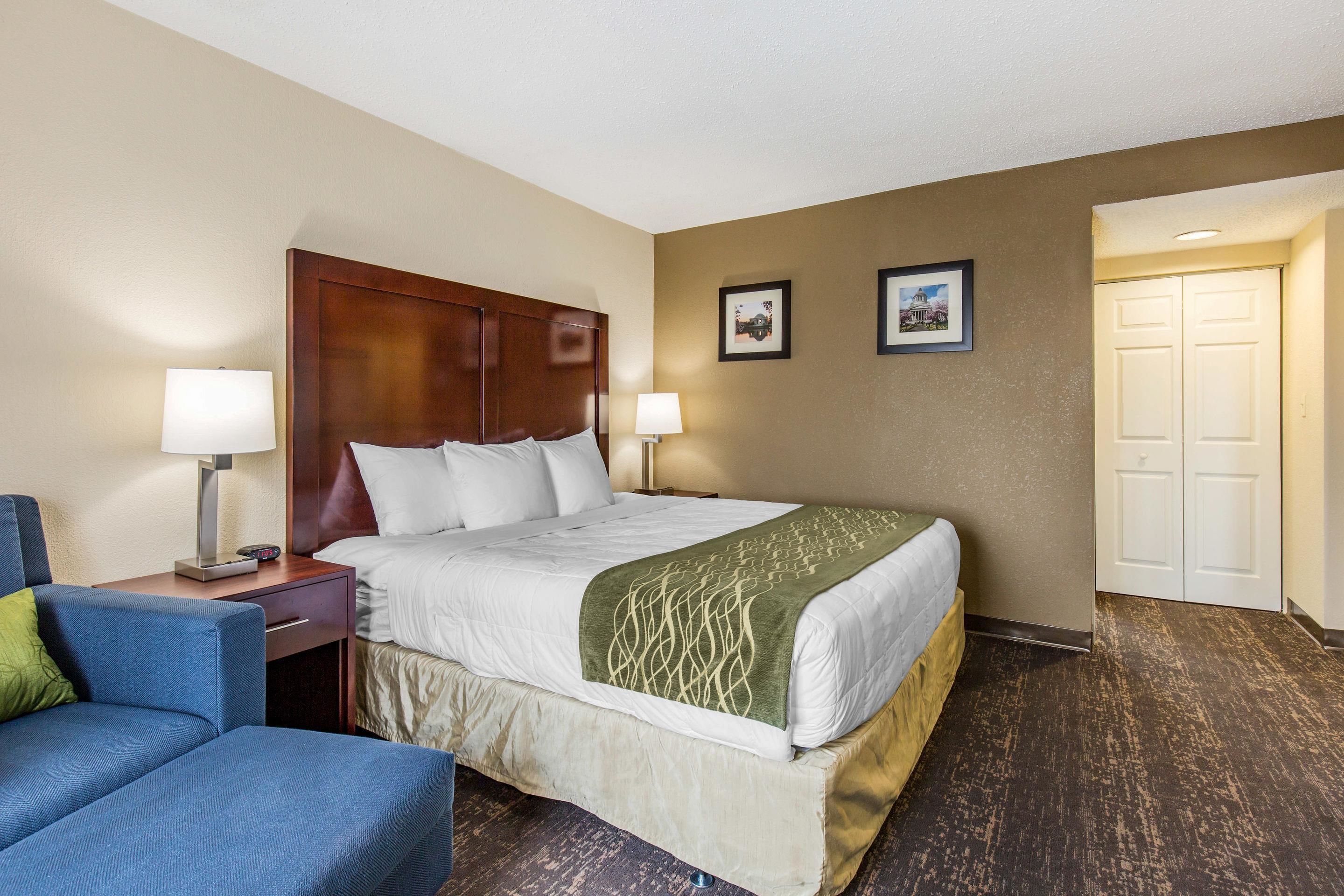 A hotel room with a bed, bedside tables, a chair, and two framed pictures on the wall.