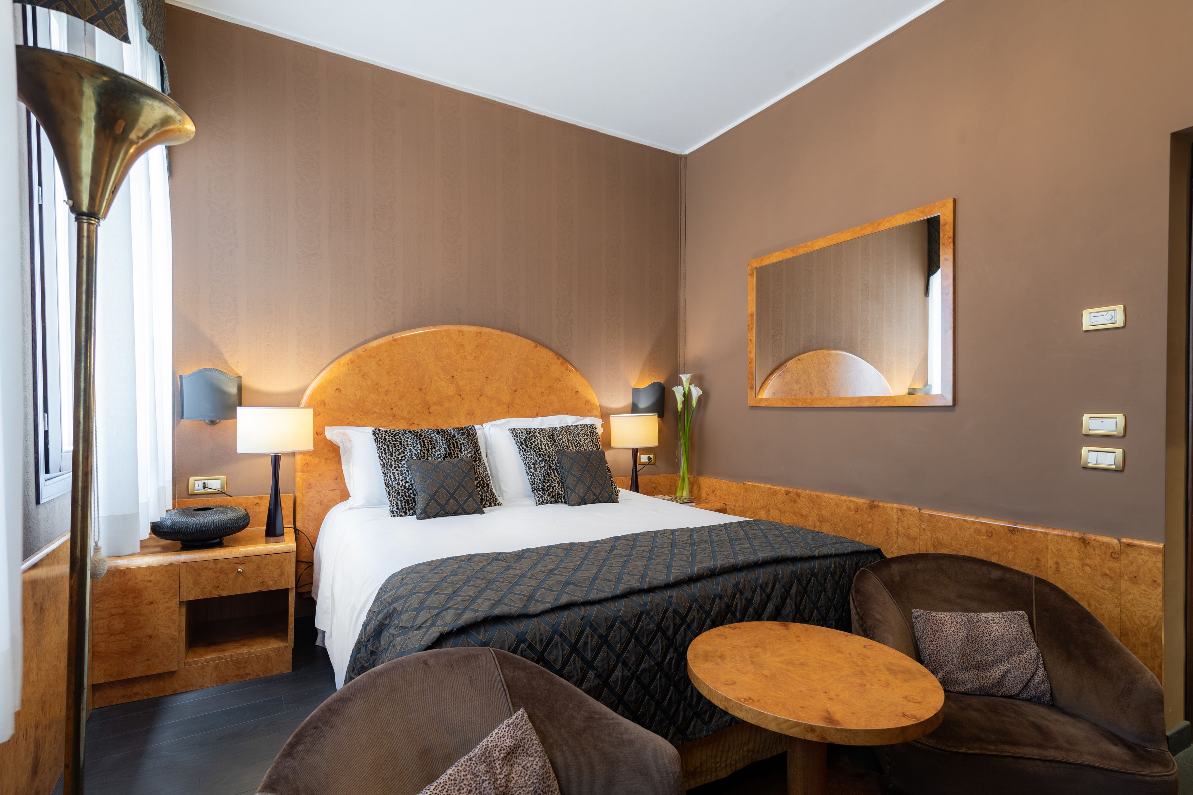 A hotel room with a large bed, two bedside tables, a round table, and two chairs.