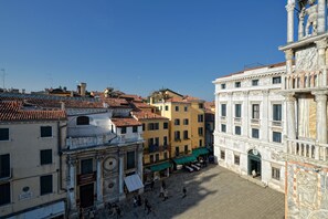 Una plaza histórica con arquitectura clásica, que incluye un edificio destacado con columnas y una estatua.