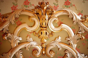 Un techo con molduras decorativas doradas y blancas muy elaboradas.
