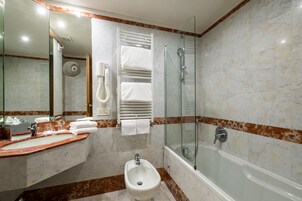Un bagno moderno con lavabo in marmo, bidet e cabina doccia in vetro.