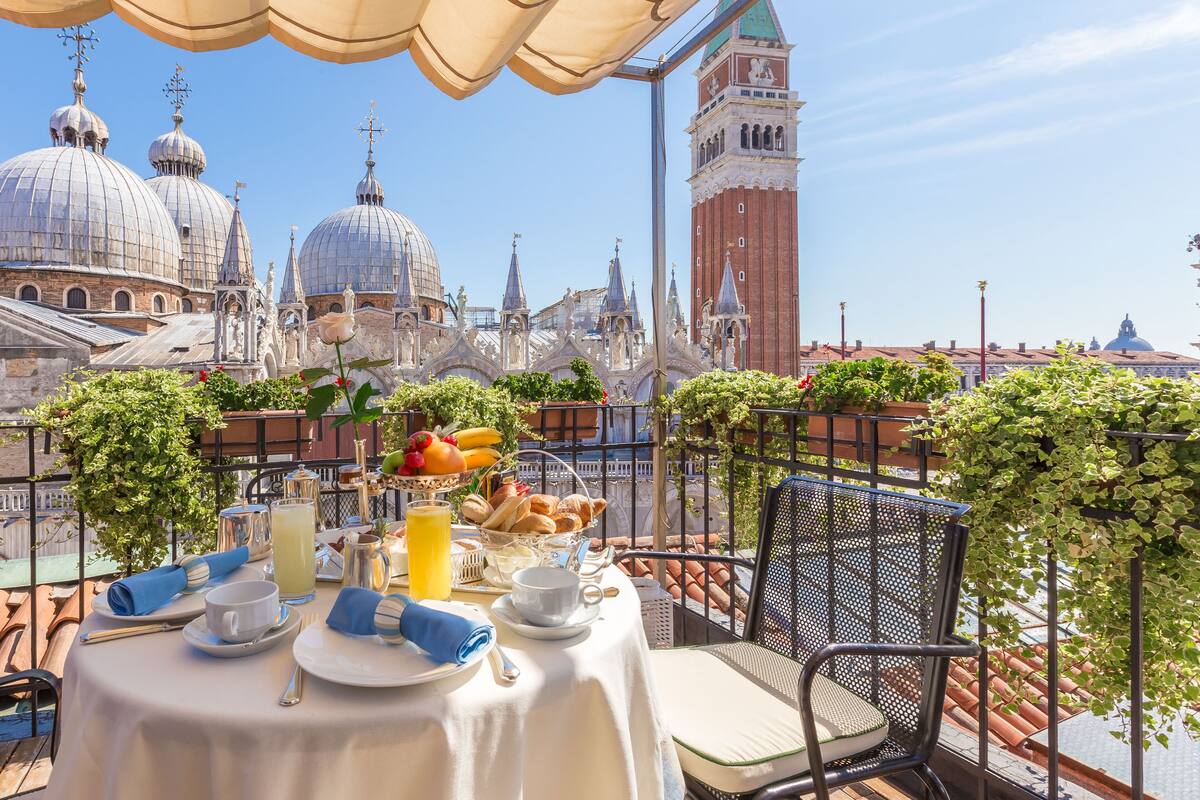A table set with breakfast items, a view of historic architecture, and a clear sky.