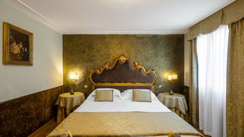 A large bed with a wooden headboard, two bedside tables with lamps, and a painting on the wall.