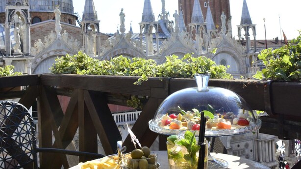 Una mesa con una bebida y fruta, frente a un fondo de arquitectura histórica.