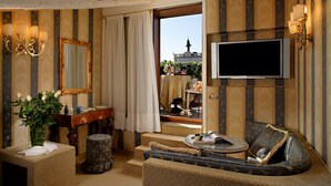 Una habitación con un espejo grande, televisor, sofá y una pequeña mesa con un jarrón de flores.