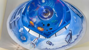 Een plafondschildering met een ruimtevaartthema, inclusief raketten en planeten.