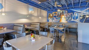 Een restaurant met zitplaatsen in hokjes en tafels, met een blauw plafond en wanddecoratie.