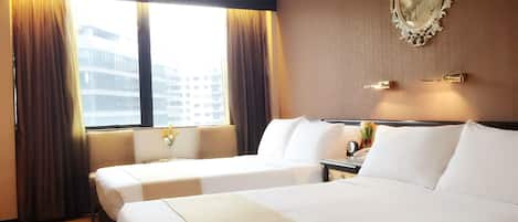 A hotel room with two beds, a large window with curtains, a wall-mounted mirror, and a small table with a vase of flowers.