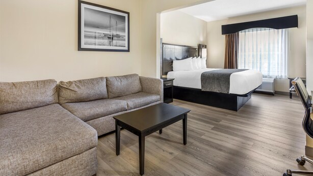 A hotel room with a large bed, a sofa, a small table, and a framed picture on the wall. - Best Western Bar Harbour Inn (Massapequa Park)
