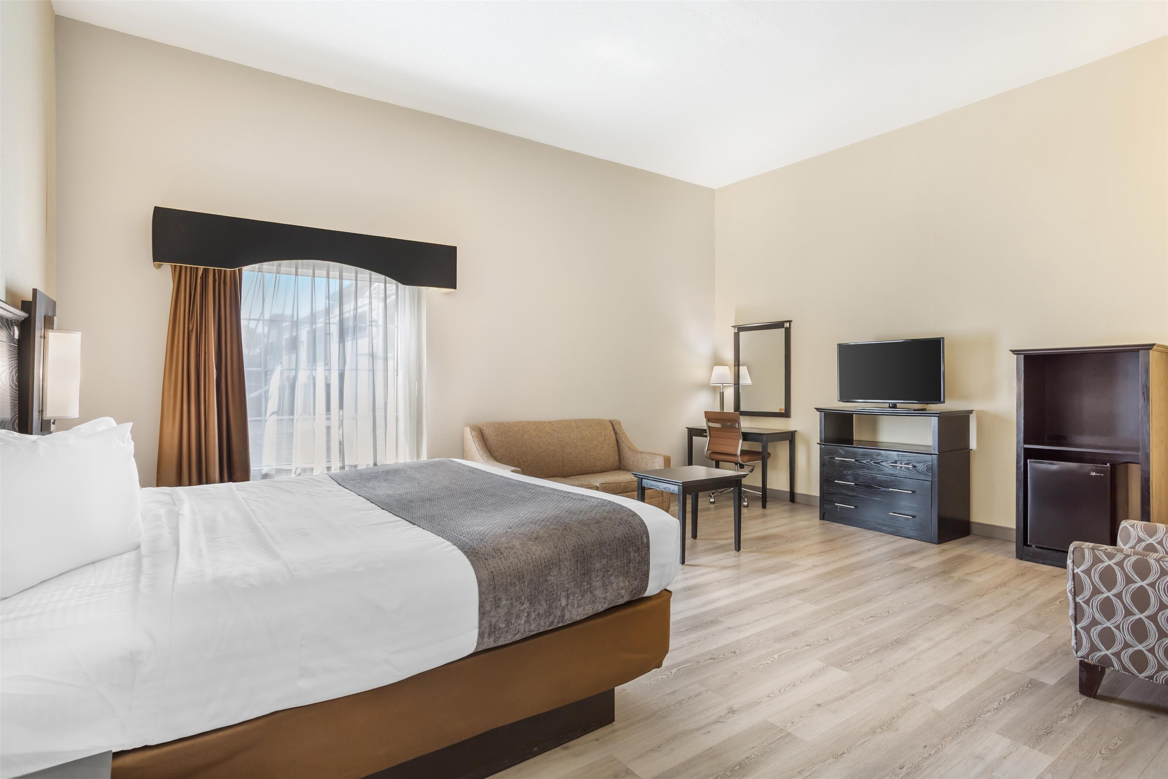 Een hotelkamer met een groot bed, een bureau, een stoel, een televisie en een kledingkast.