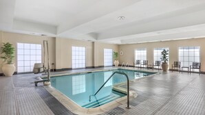 An indoor swimming pool with clear glass walls, tiled floor, and several potted plants. - Best Western Bar Harbour Inn (Massapequa Park)