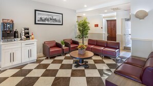 A lobby with a checkered floor, leather seating, a coffee machine, a framed cityscape, and a plant centerpiece. - Best Western Bar Harbour Inn (Massapequa Park)