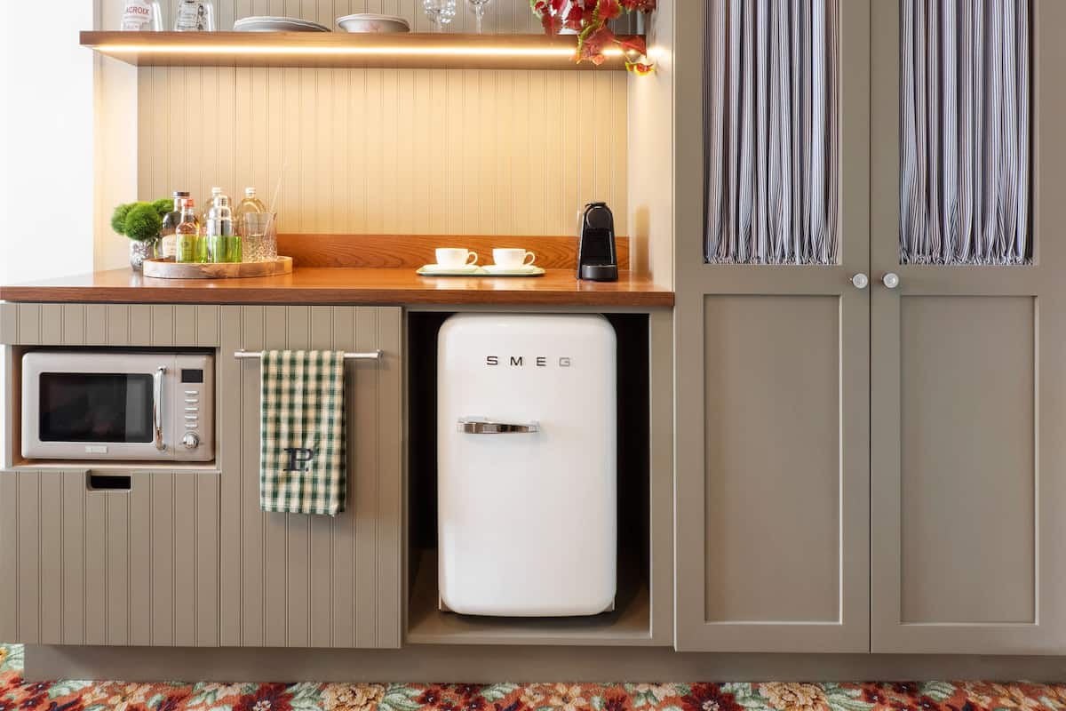 Een kleine keuken met een magnetron, een koelkastje en een houten aanrecht.