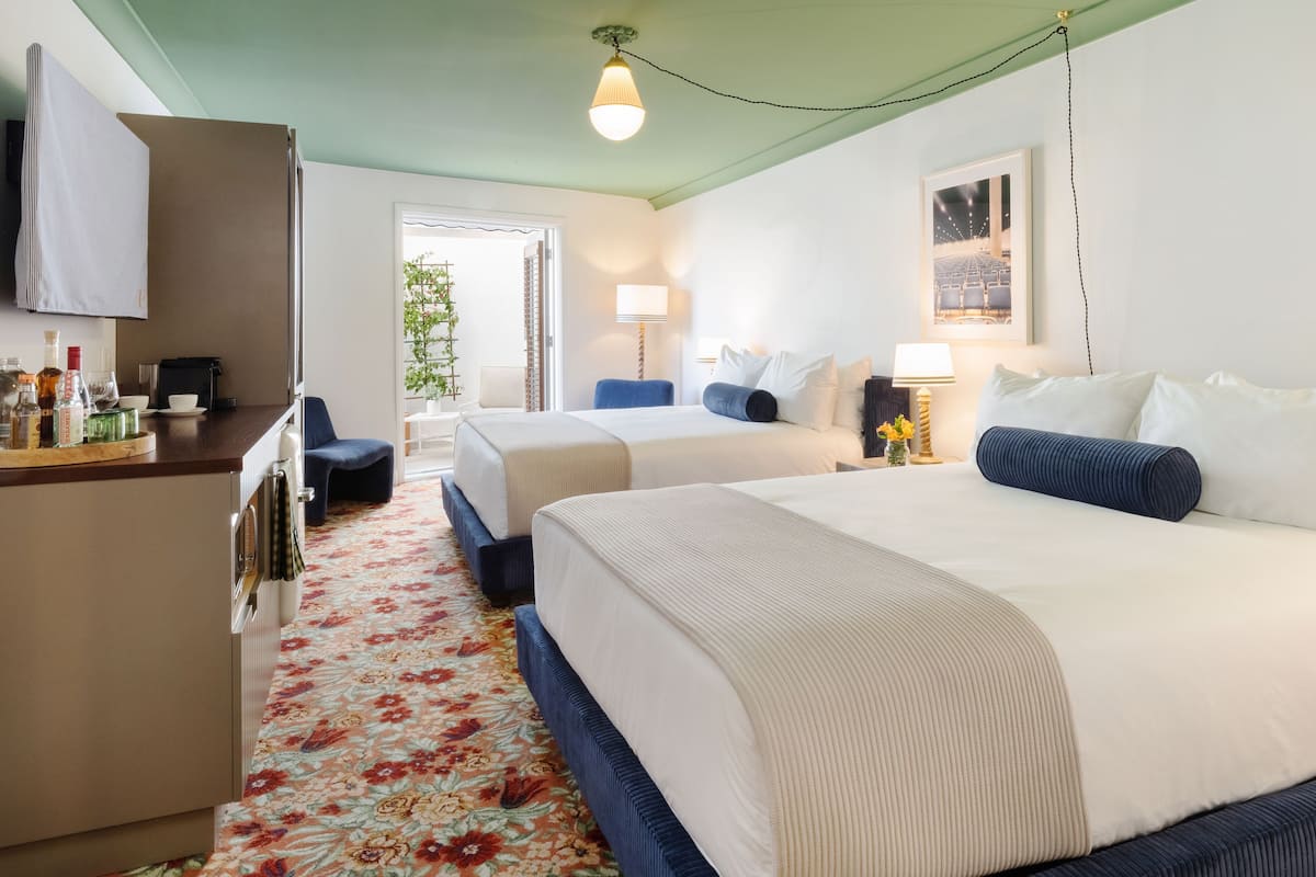Een hotelkamer met twee bedden, een bureau met een computer, een koelkast en een raam met uitzicht op het omliggende landschap.