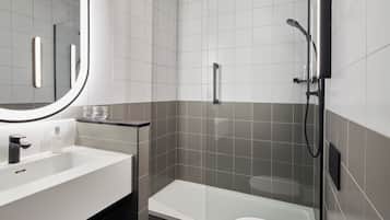 Un baño moderno con lavamanos blanco, cabina de ducha con mampara de vidrio y un inodoro.