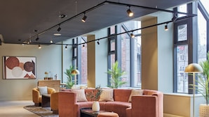 Een moderne woonkamer met een hoekbank, een salontafel en een vloerlamp. Er zijn grote ramen met uitzicht op de stad.
