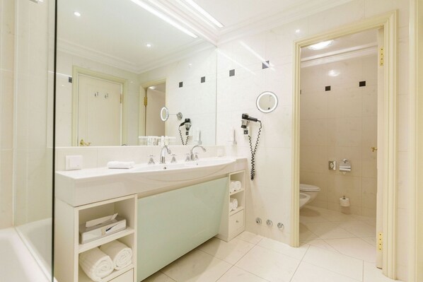 A modern bathroom with a large mirror, dual sinks, a toilet, and a shower area.
