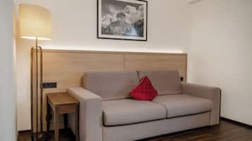 Quarto moderno com sofá, mesa lateral, abajur e quadro na parede.