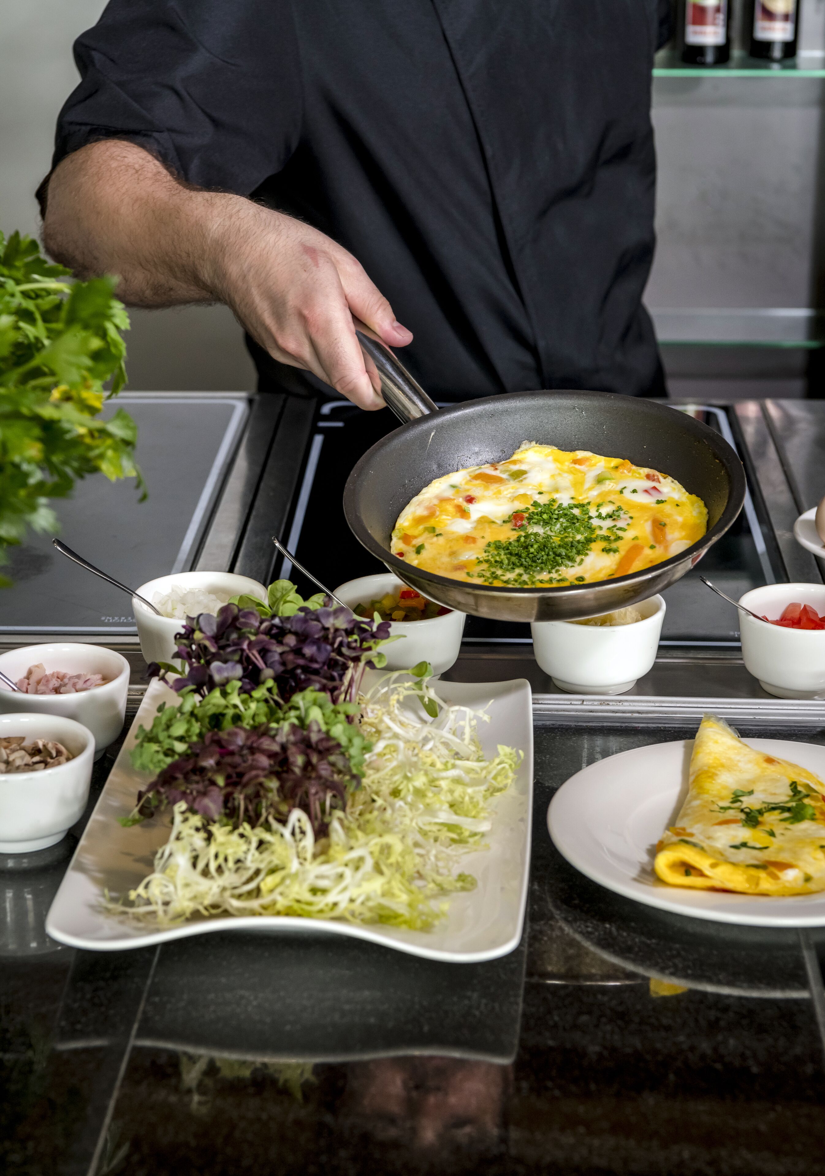 A chef cooking an omelette on a stove in a kitchen.