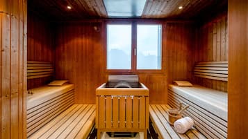 A sauna with wooden benches and a central bench, large windows, and a skylight.