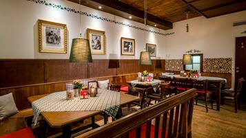 Un ristorante con tavoli e panche in legno, quadri appesi alle pareti e lampade a sospensione.