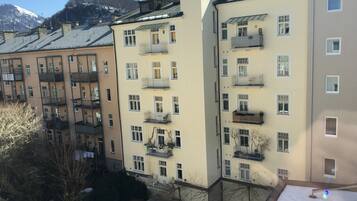 A multi-story residential building with balconies, a snow-covered roof, and a mountain in the background.