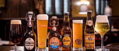 A selection of beer bottles and glasses on a wooden table in a bar setting.